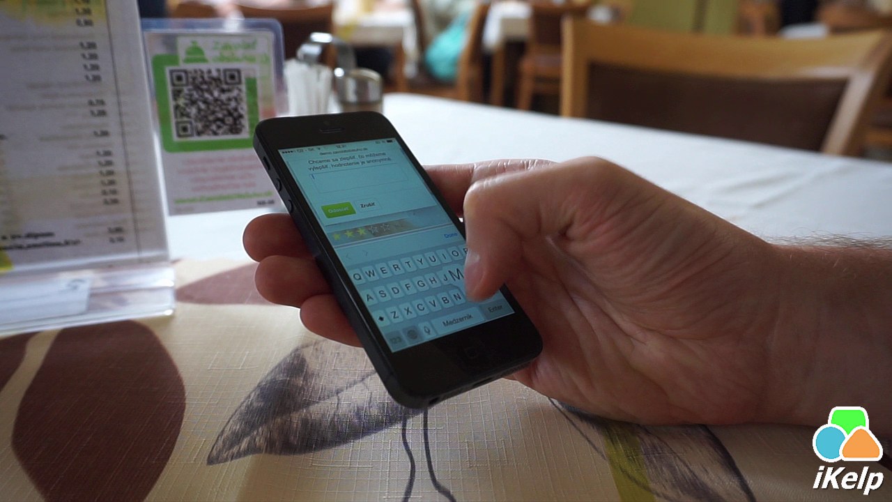 Hosť píše textový komentár k hodnoteniu na klávesnici smartfónu, na obrazovke je viditeľné textové pole a tlačidlá Odovzdať a Zrušiť